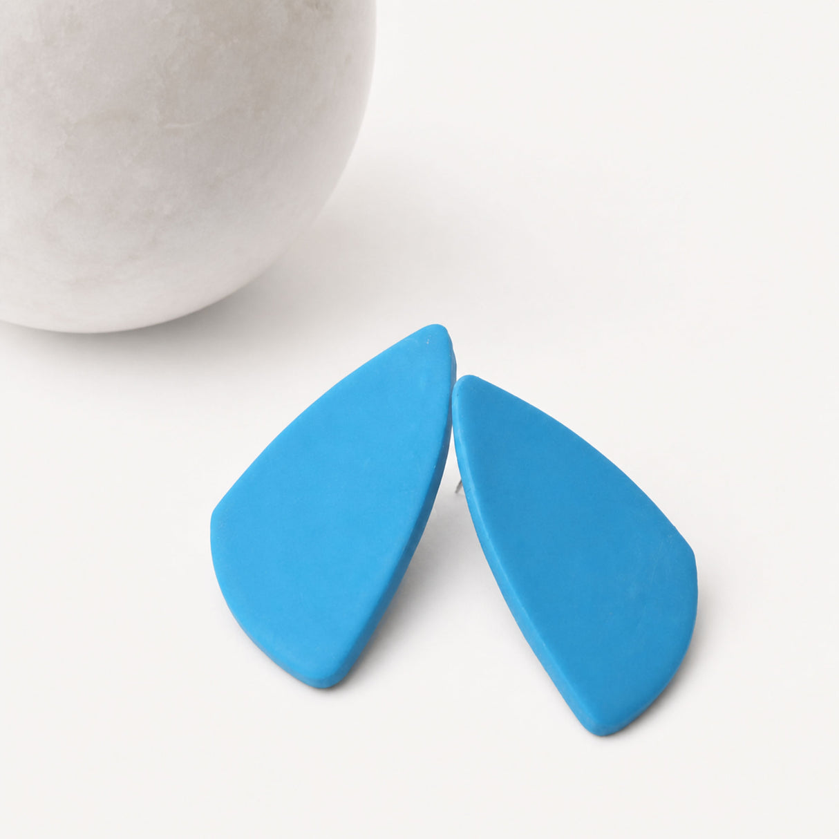 Blue geometric statement stud earrings on a white background