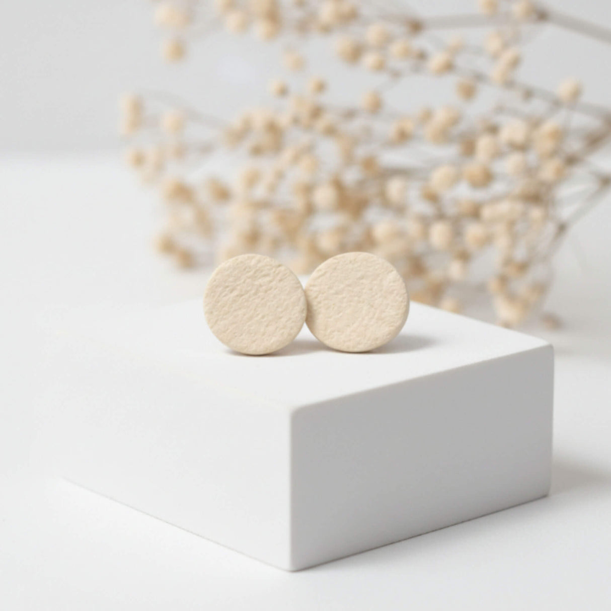 small cream stud earrings on plinth, handmade clay jewellery at lottie of london