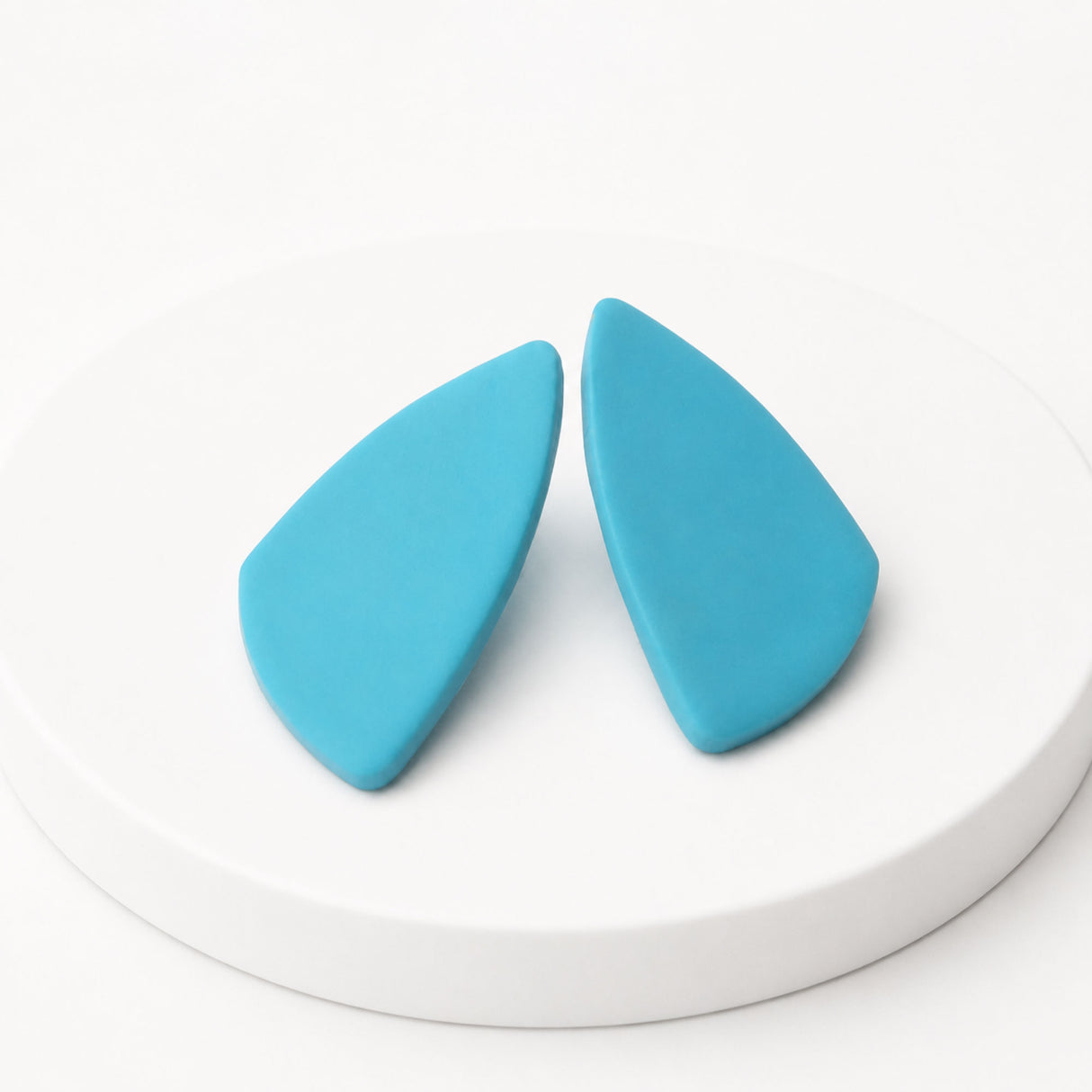 turquoise blue geometric statement stud earrings on plinth