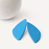 Blue geometric statement stud earrings on a white background